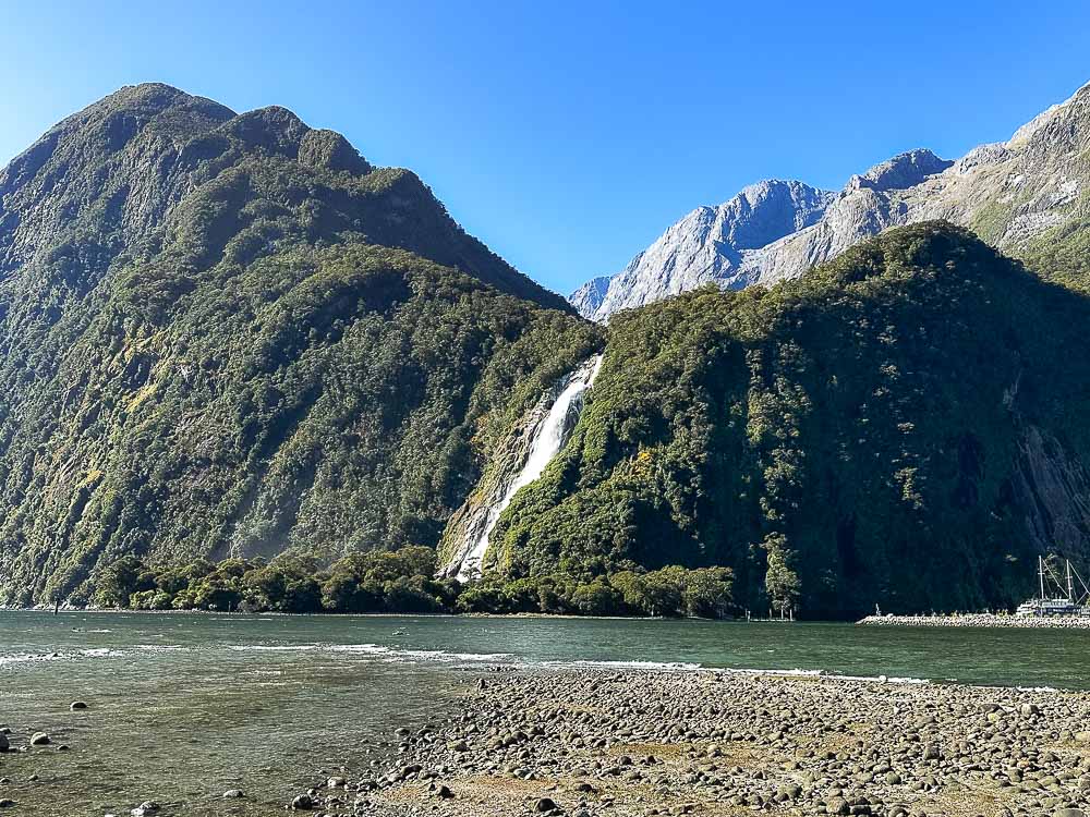 large waterfall on tree covered mountain