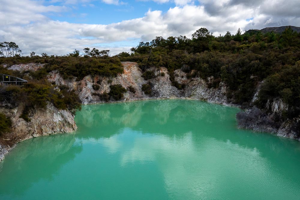 Devil's Bath, a vivid green geothermal pool surrounded by rocky terrain at Wai-O-Tapu Thermal Wonderland near Rotorua, New Zealand.