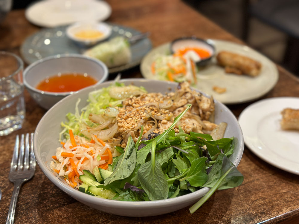 Bowl Vietnamese chicken noodles with a side of greens. 