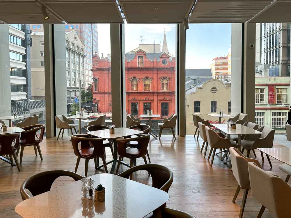 The open plan dining area in the Holiday Inn Express Hotel in Auckland CBD, with floor to ceiling glass showcasing views of the heritage buildings across the road.