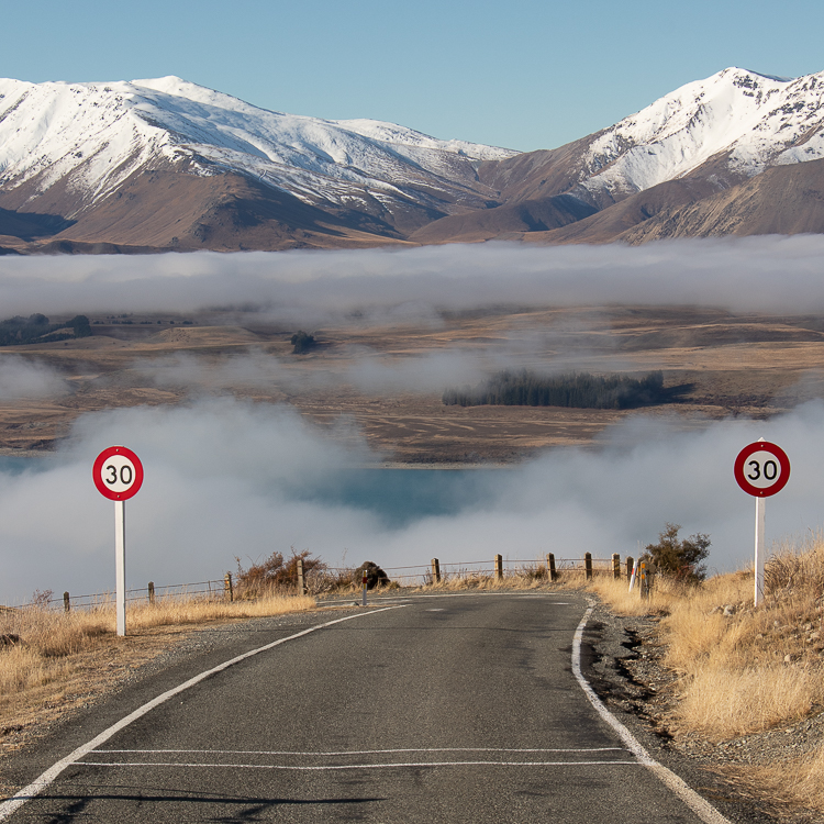 Godley Peaks Road, Lake Tekapo on a foggy day with snow capped mountains in the background.