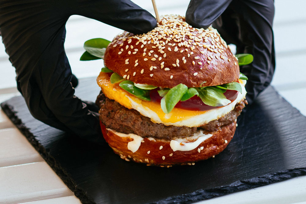 close up of a kiwi burger with egg and beetroot on a sesame seed bun.