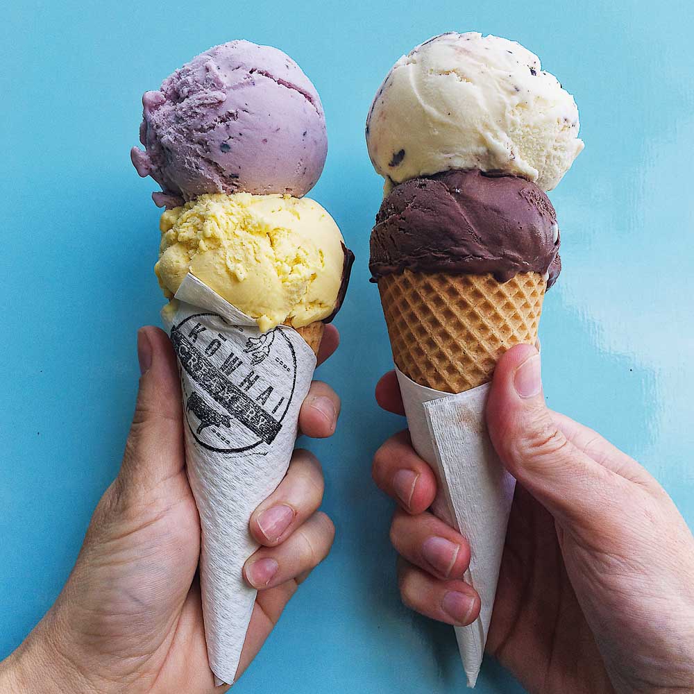 two hands each holding an ice cream cone