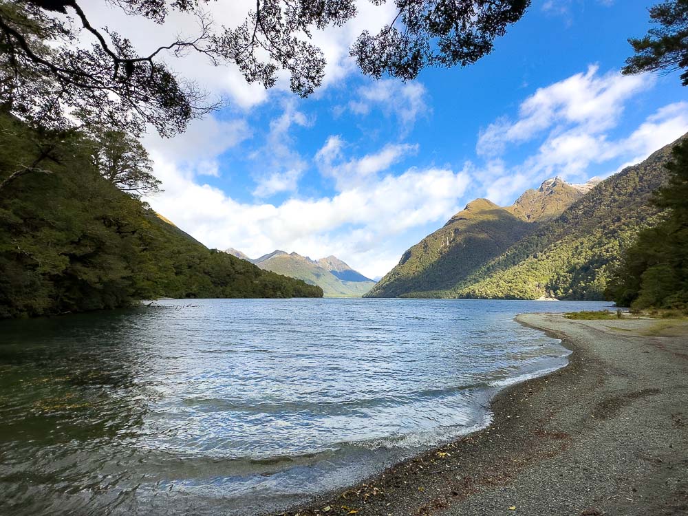 lake with pebble shoreline and mountains in the background