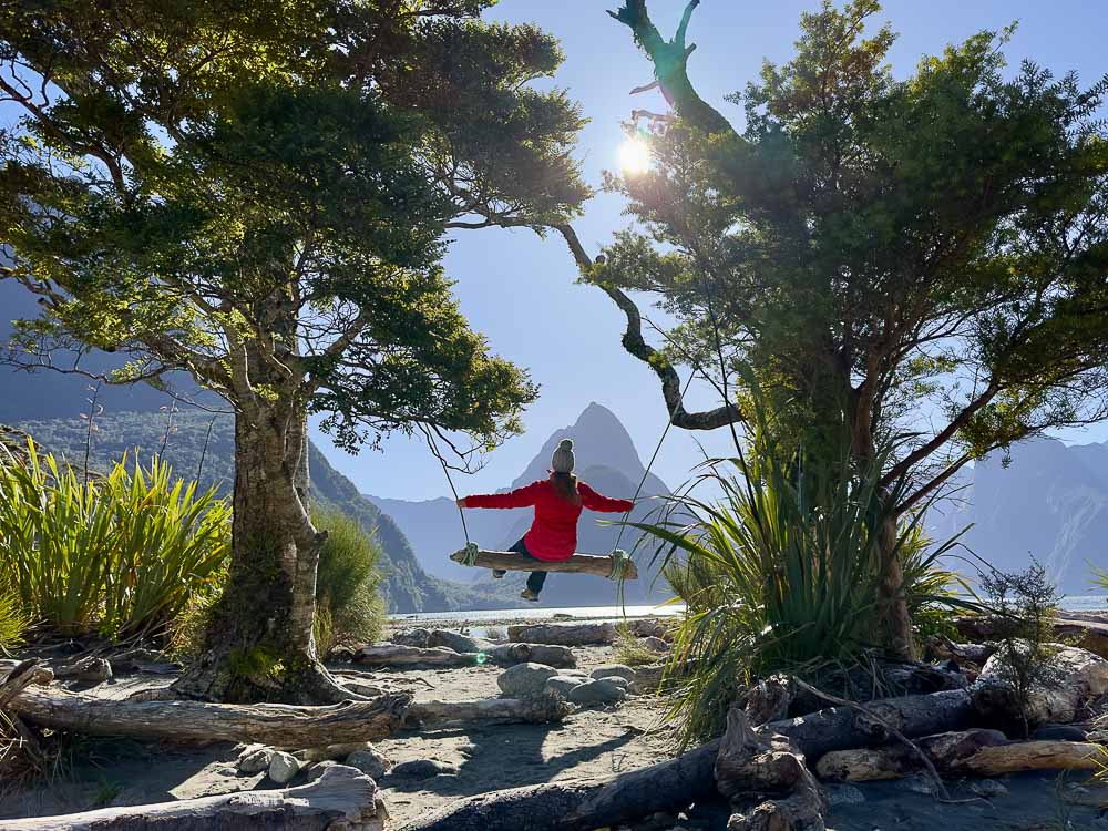 girl on wooden swing with mountains in the background.