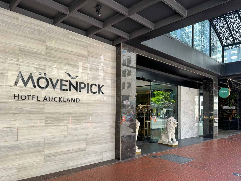 Exterior of the Movenpick Hotel Auckland front entrance with medium sized white lion statues on each side of the entrance.