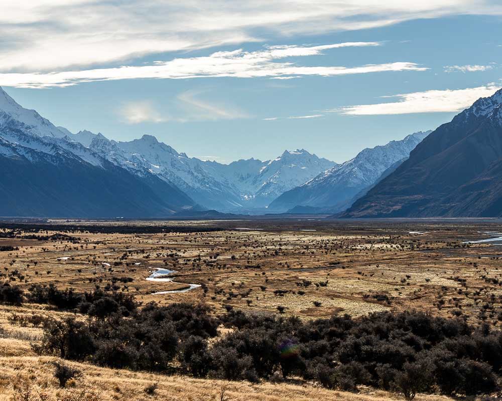 Braided rivers on the floor of a golden valley backed by snow covered mountains in Mt Cook National Park.