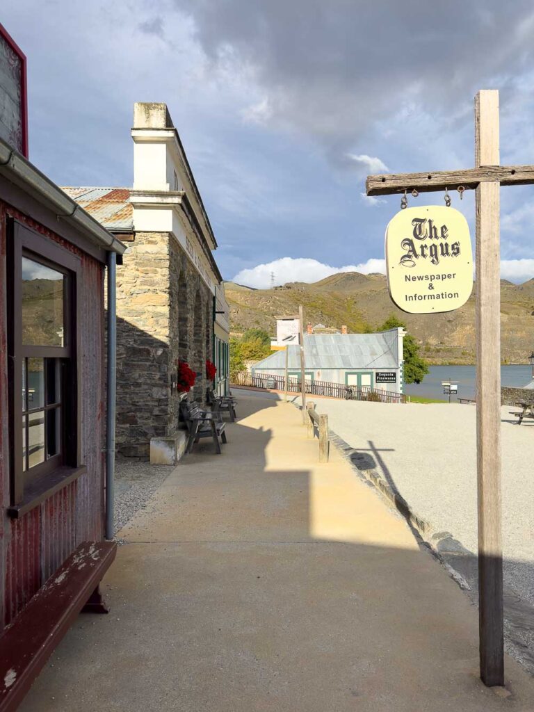 Looking down the sidewalk alongside heritage buildings in Cromwell with a sign that says The Argus Newspaper & Information.
