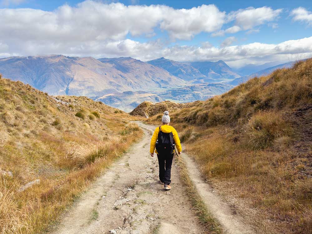Girl in yellow jacket walking down a mountain path