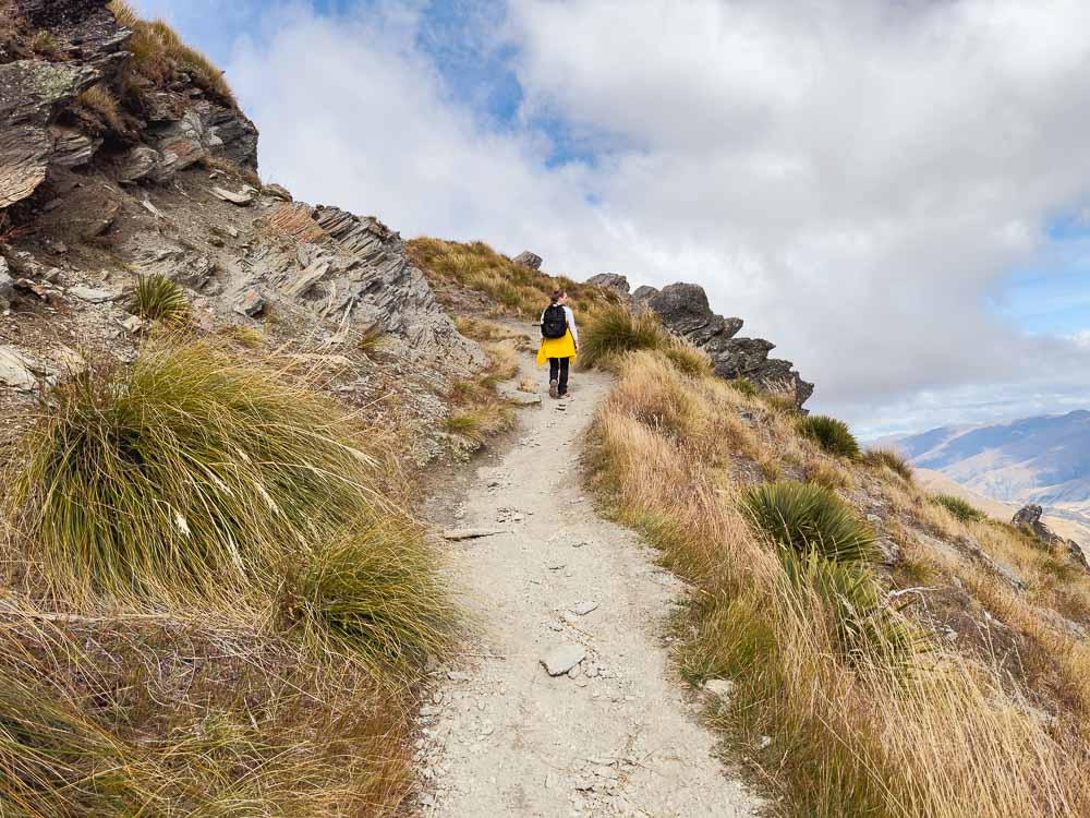girl hiking up a mountain on a gravel path