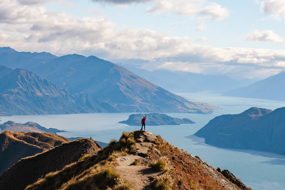 girl standing on mountain with arm in the air