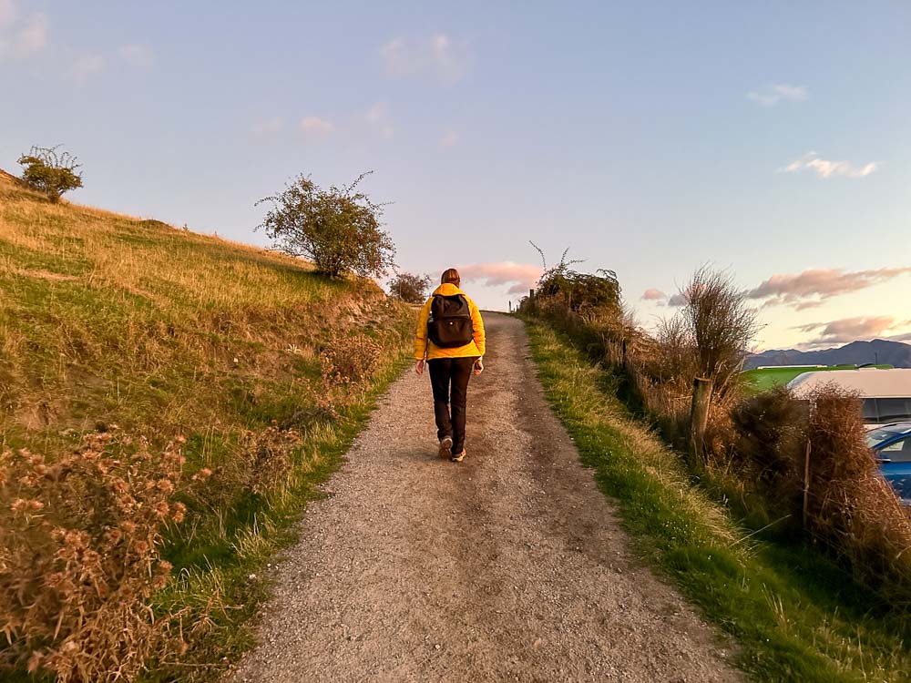 girl in yellow jacket walking up a path at sunrise