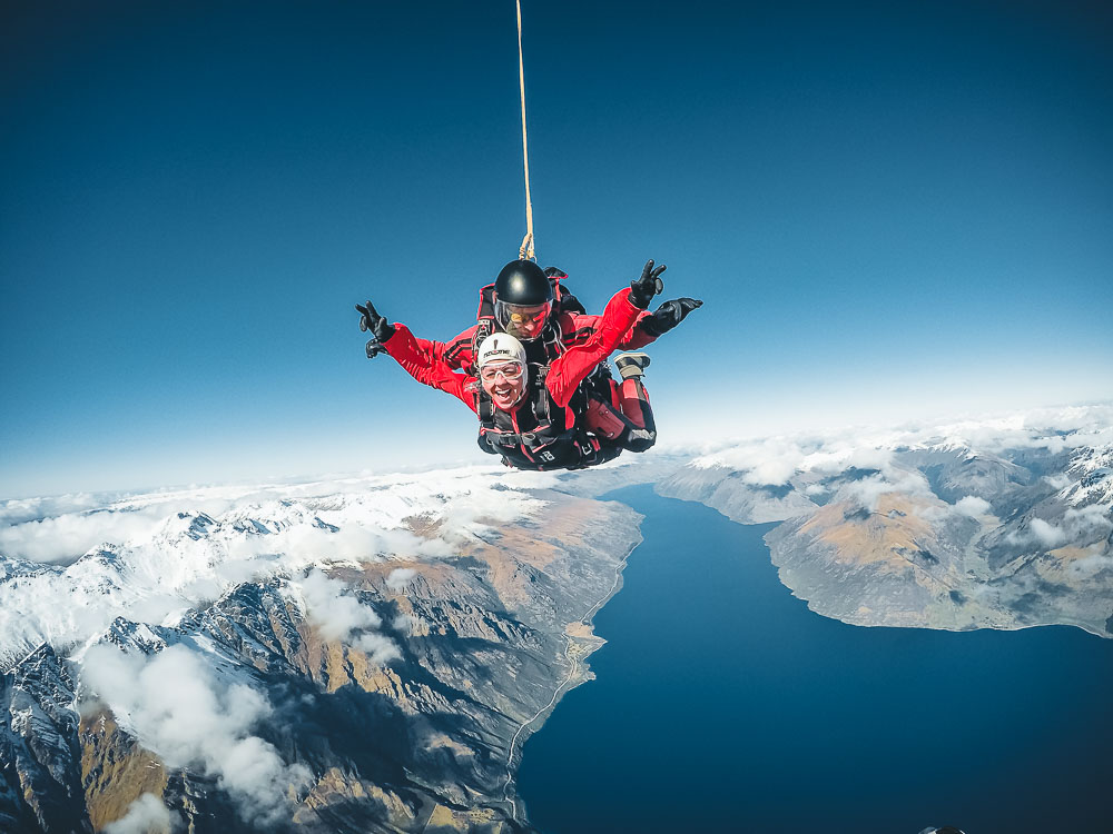 A photo me tandem skydiving over snow capped mountains and Lake Wakatipu in Queenstown New Zealand on a clear day. 