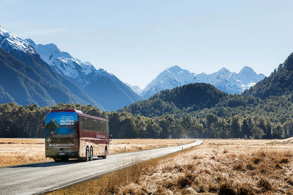 bus driving along remote road with mountains in background